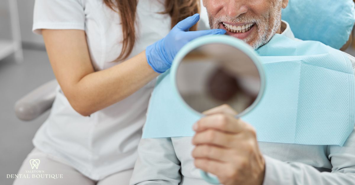 Senior dental patient checking his restored smile after dental implant treatment.