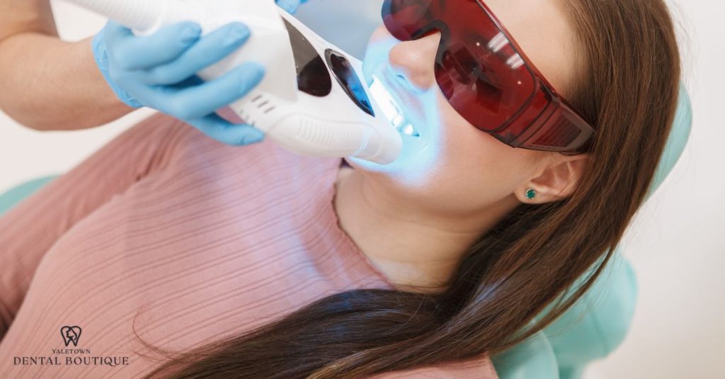A dentist performs a professional teeth whitening procedure on a patient