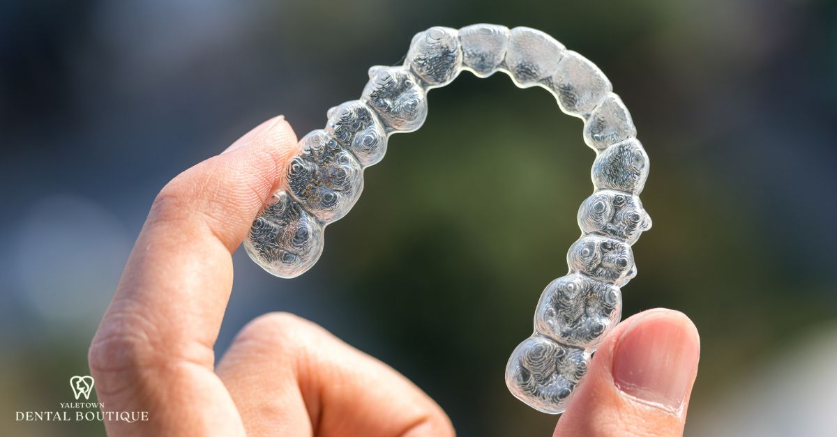 Close-up of a clear Invisalign aligner being held, showing how Invisalign works to straighten teeth discreetly.