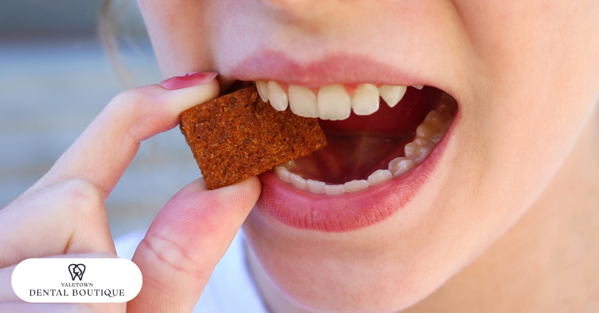 Close-up of a person biting into a hard snack, an example of the worst foods to avoid after implant surgery.