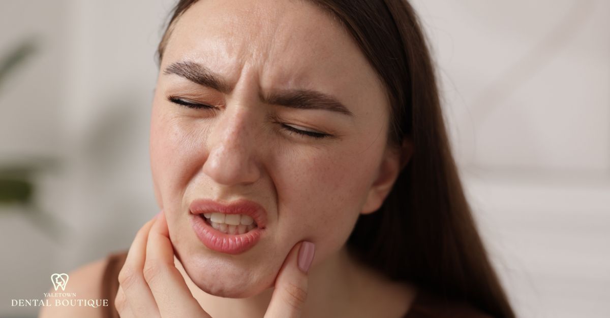 Close-up of jaw clicking symptoms as a woman presses her jawline, indicating possible TMJ irritation
