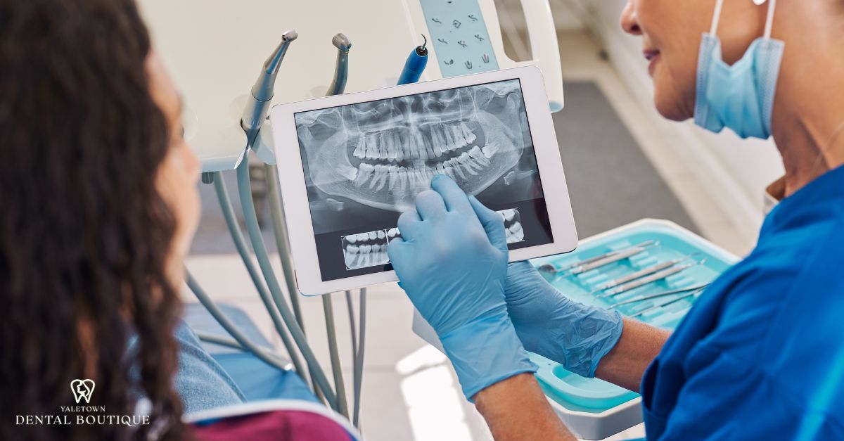 Dentist reviewing dental X-ray with patient to detect cavities between teeth