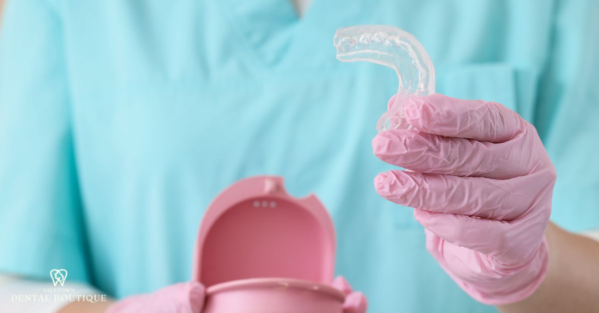 Dental professional holding a clear night guard used for non-surgical gum recession stabilization