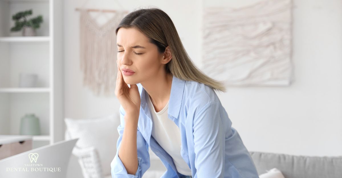 Person experiencing lower teeth pain and jaw sensitivity at home